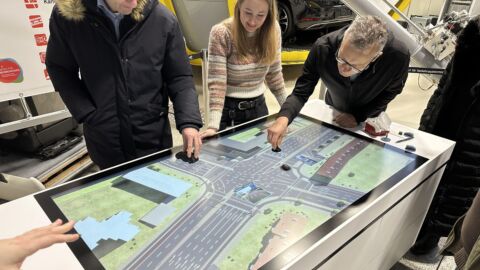 Personen stehen um eine Straße auf einem Bildschirm auf einem Tisch