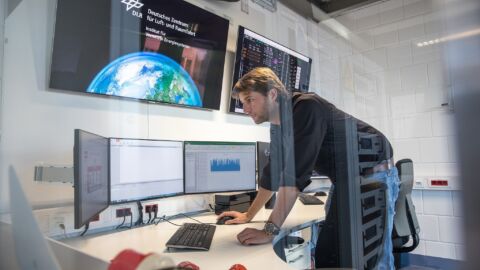 Person steht vor mehreren Bildschirmen