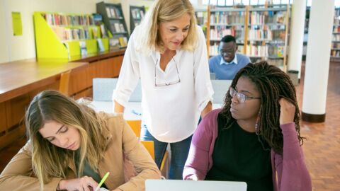 Drei Frauen an einem Tisch in einer Bibliothek